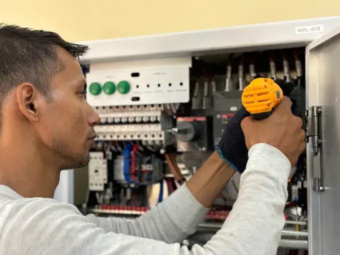 Electrician using a cordless driver on a breaker panel